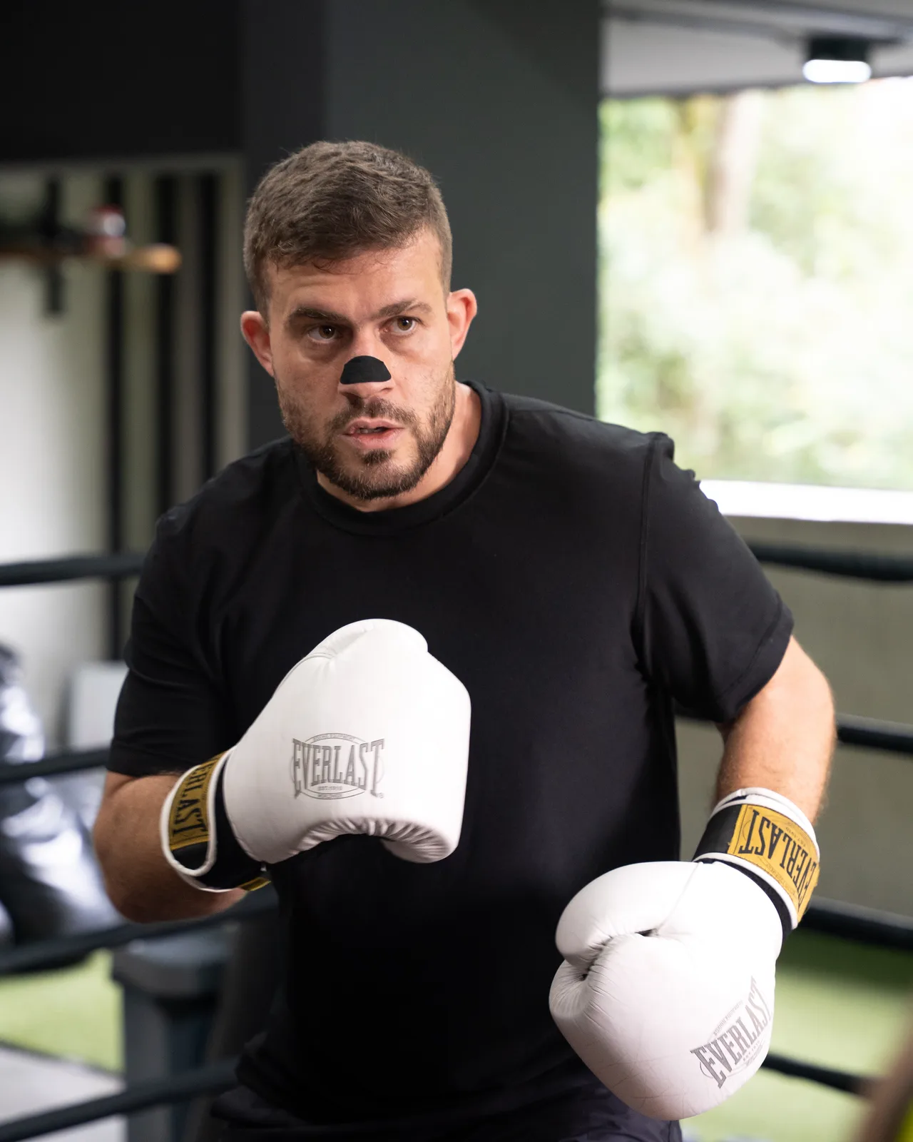 Athlete training in a boxing ring wearing the Breathe-More nasal strip